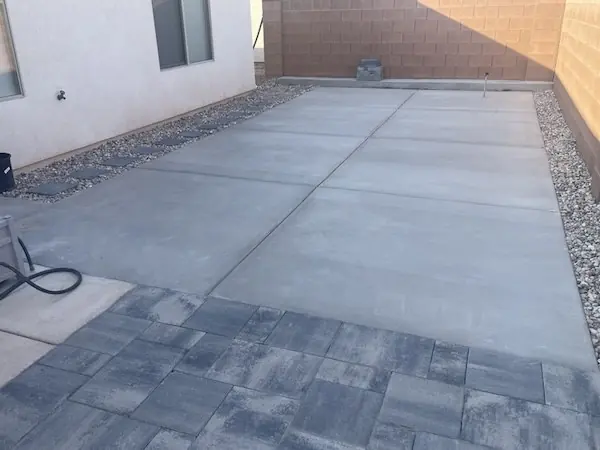New concrete patio slab with a gray paver border in a side yard