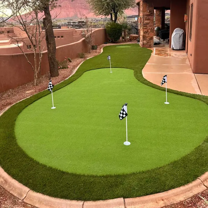Close view of a backyard putting green with checkered flags and a concrete curb