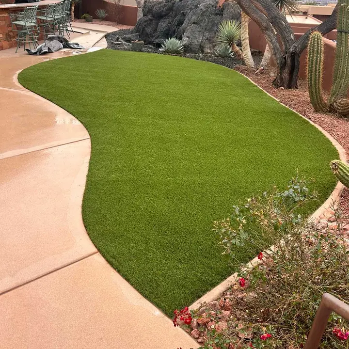 Curved artificial turf lawn along a concrete path with a cactus and a rock outcrop